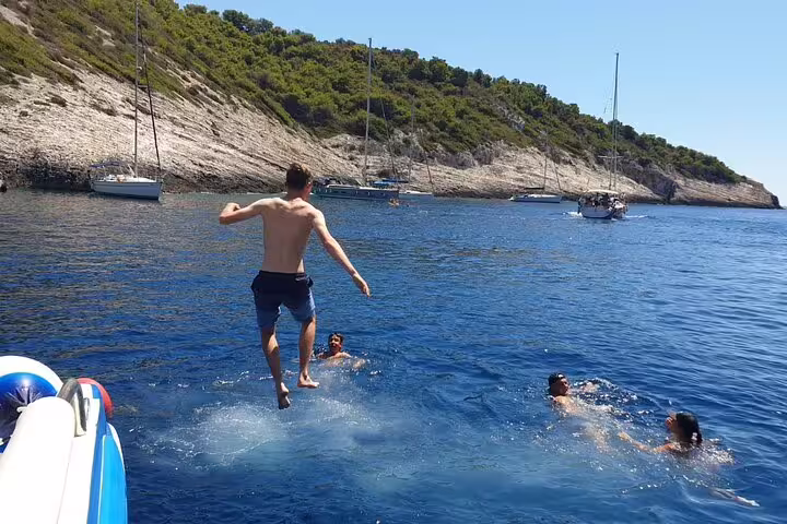 Traveler jumping into Adriatic near Vis, swimming stop on Scheduled Blue Cave & 5 Islands tour from Split