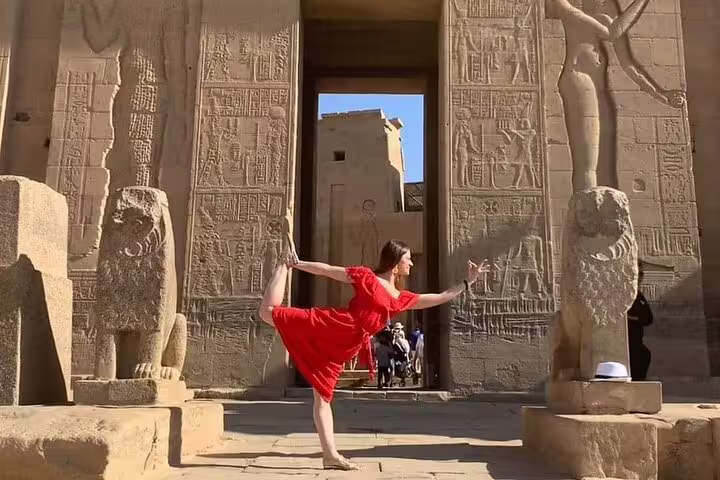 Traveler in red dress posing at Edfu Temple entrance, Luxor to Edfu and Kom Ombo day tour Egypt