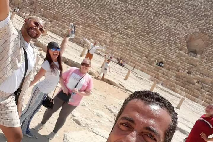 Happy travelers selfie beside the Great Pyramid of Giza during a half-day pyramids tour with guide