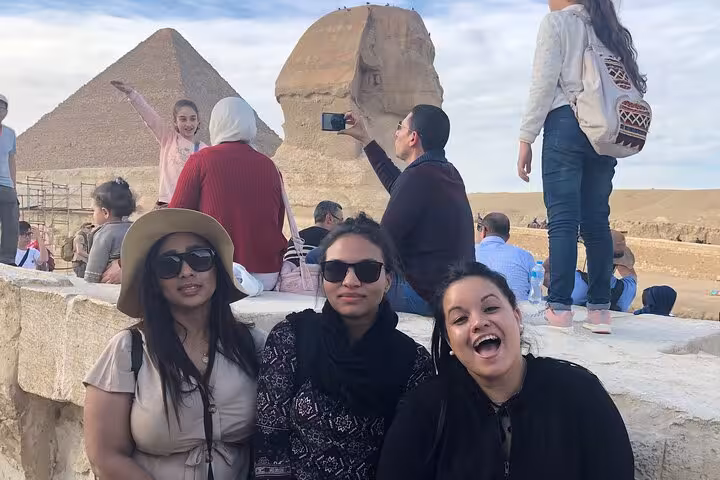 Travelers posing by the Great Sphinx with Giza Pyramid backdrop on Great Pyramid and Saqqara Serapeum tour