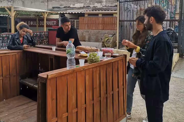 Travelers enjoy aperitif snacks after petanque in Marseille, social Provençal experience in Le Panier