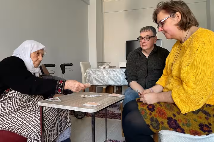 Travelers play cards with a local Turkish grandma at home, enjoying authentic afternoon Turkish tea experience