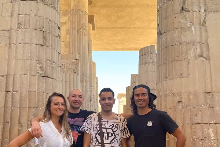 Travelers posing between ancient Saqqara columns on private tour to Dahshur pyramids, Memphis and Saqqara from Cairo