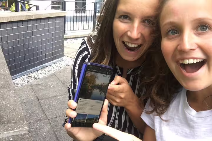 Two travelers show a smartphone clue for an e-scavenger hunt London, self-guided city exploration game