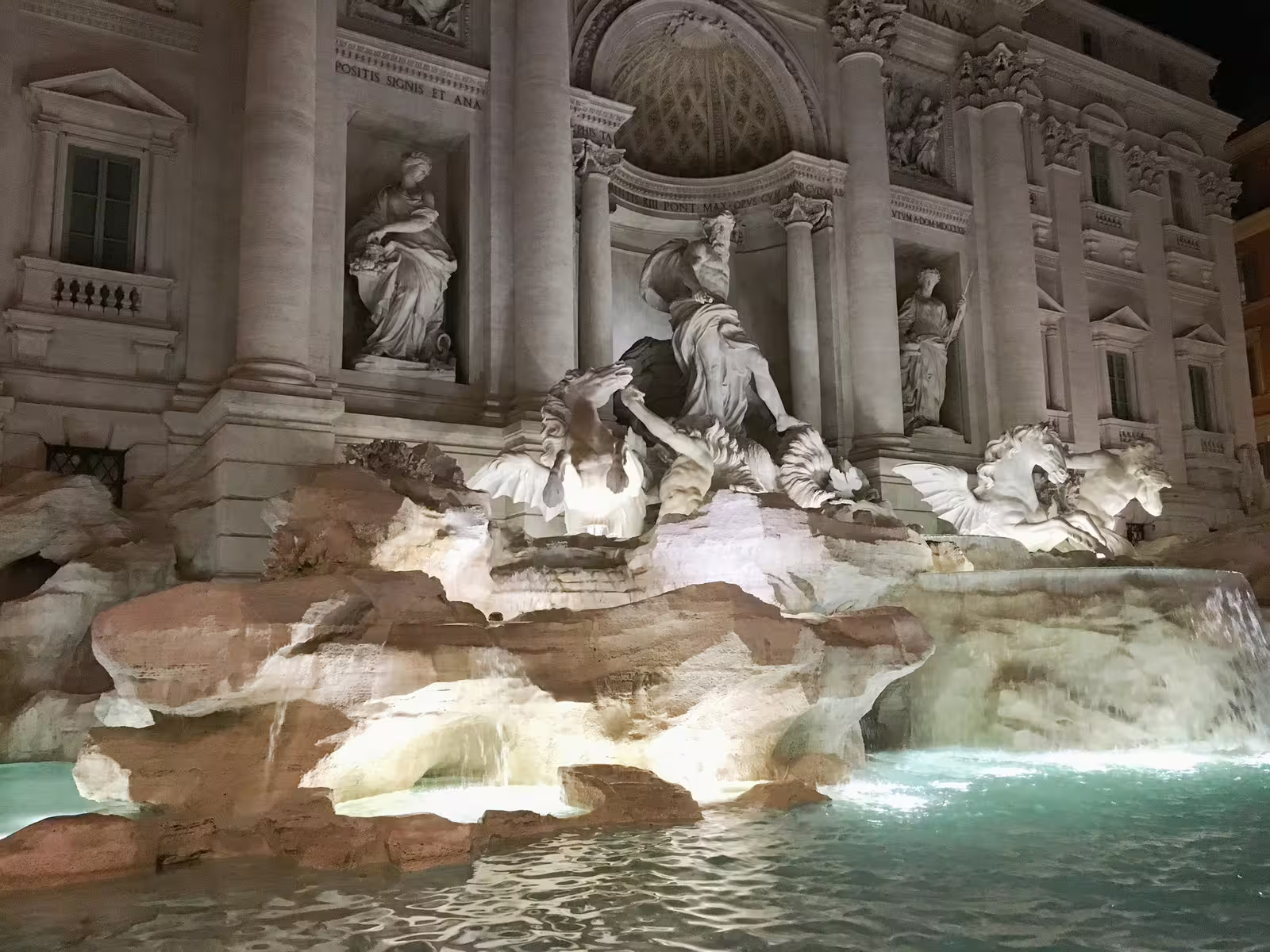 Night view of Rome’s Trevi Fountain with illuminated Baroque statues and turquoise water on an evening walking tour stop