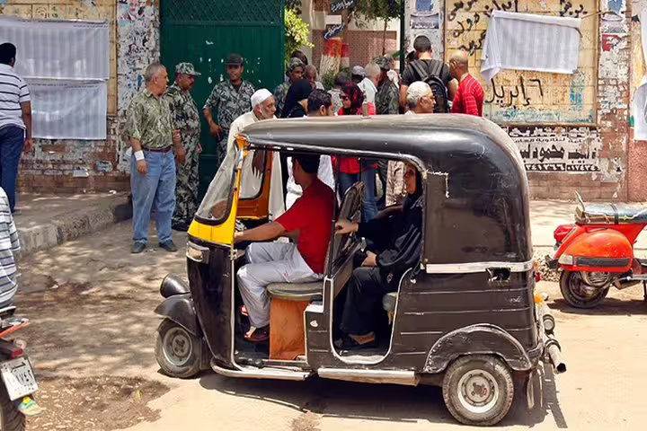 Tuk tuk with passengers in an Egyptian neighborhood street scene, guided Cairo tuk tuk tour with local culture