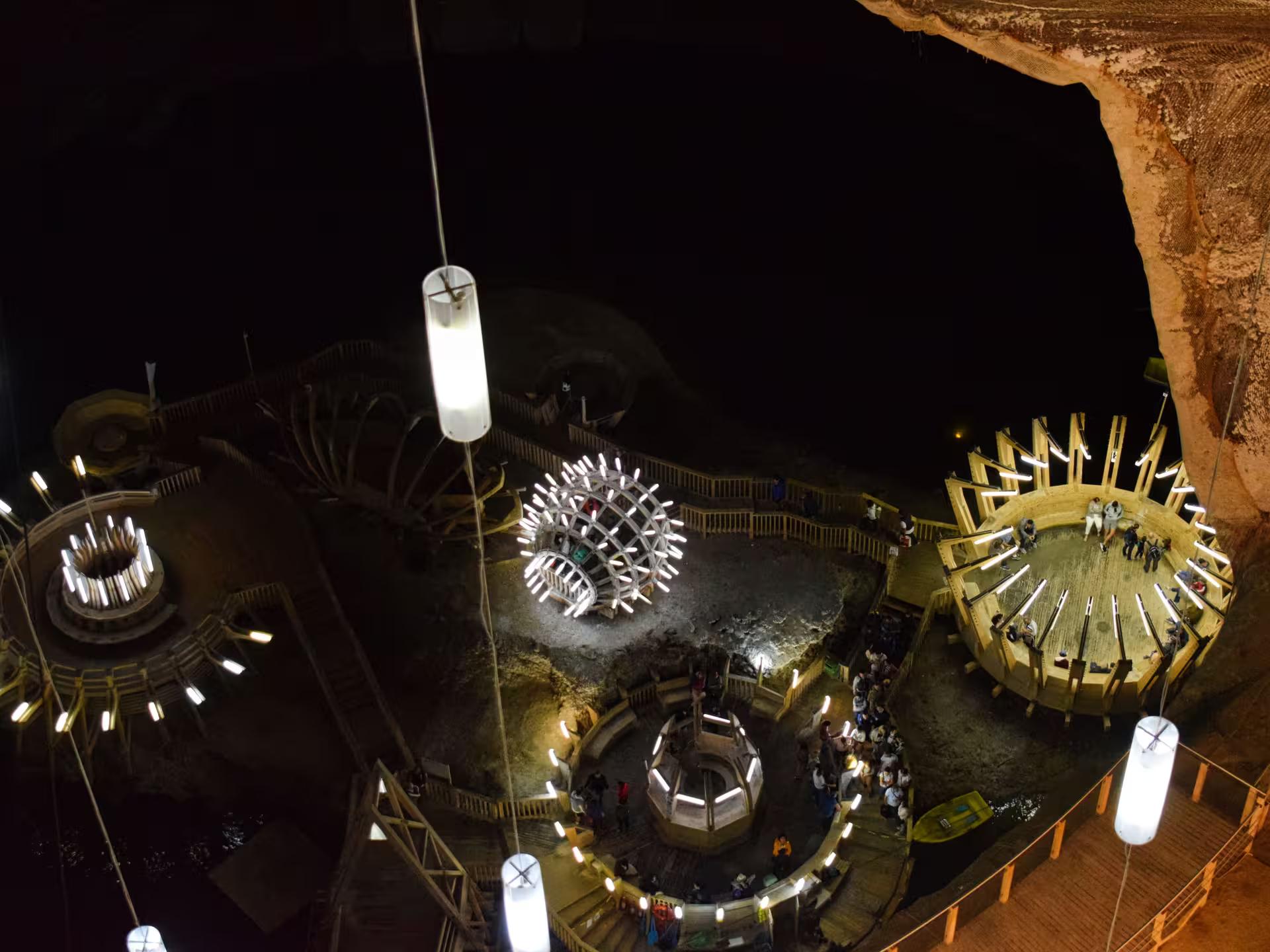 Aerial view of Turda Salt Mine interior with glowing wooden structures and tourists exploring underground