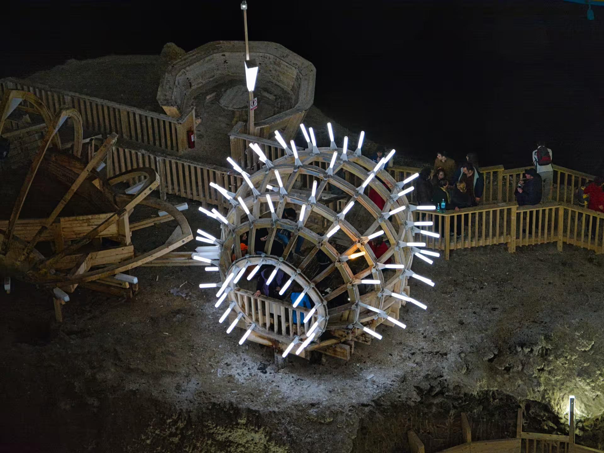 Illuminated wooden ferris wheel installation inside Turda Salt Mine Romania on a full-day tour from Cluj
