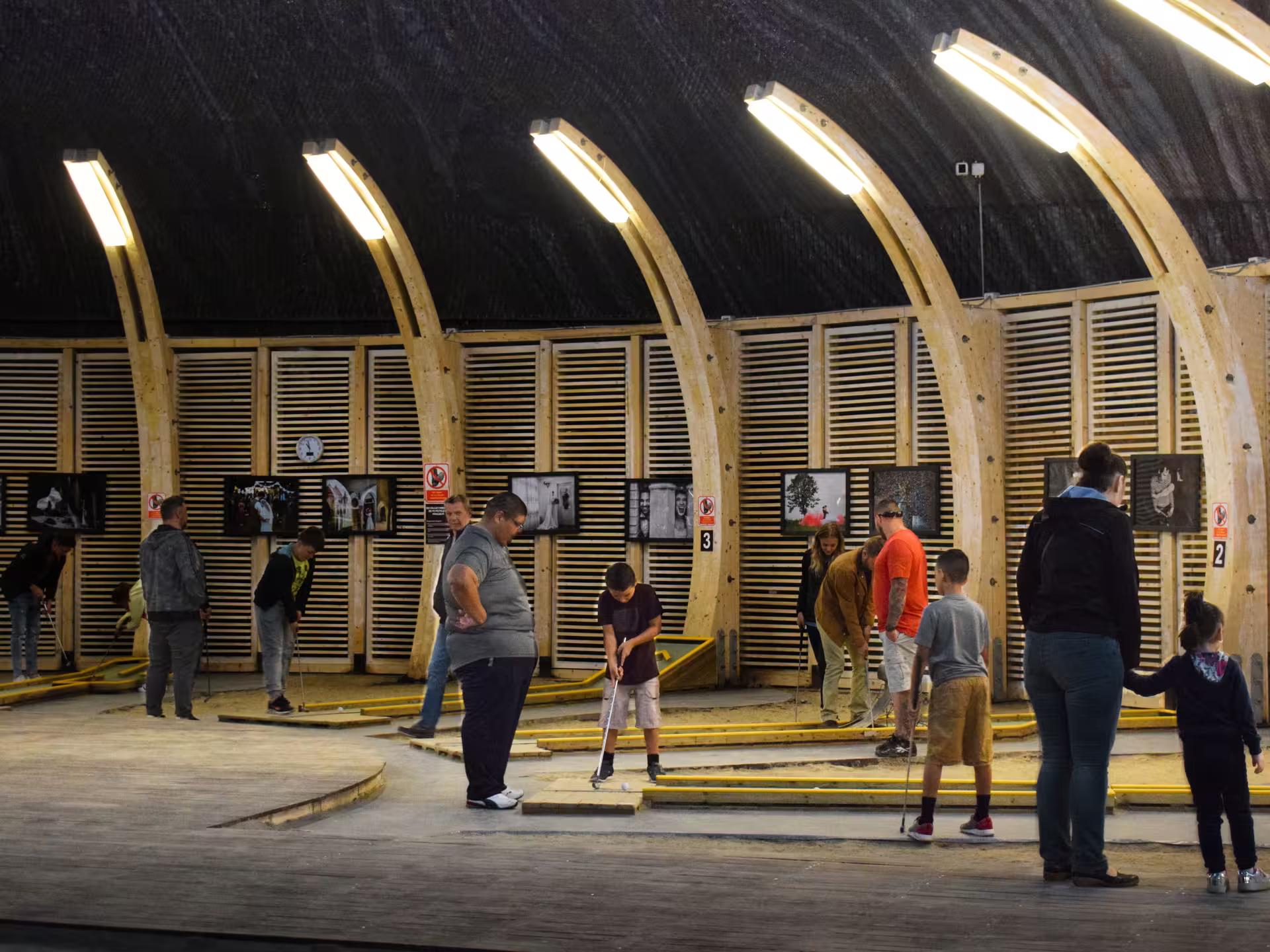 Visitors playing mini golf inside the illuminated wooden arched hall of Turda Salt Mine Romania full-day tour
