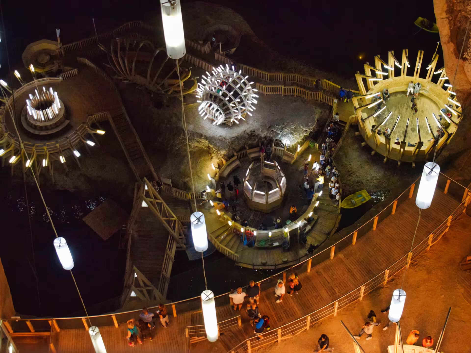 Aerial view of Turda Salt Mine's stunning underground chamber with wooden structures and glowing lights