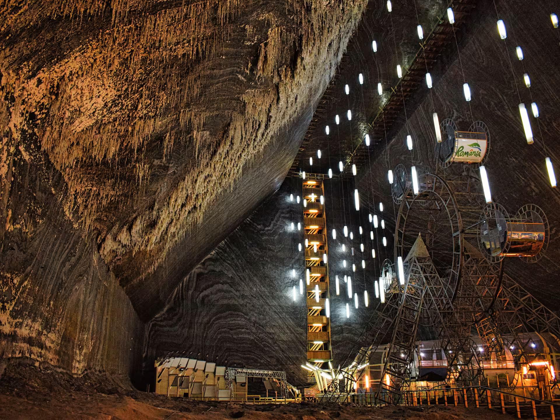 Massive underground chamber with Ferris wheel and lights at Turda Salt Mine guided tour from Cluj