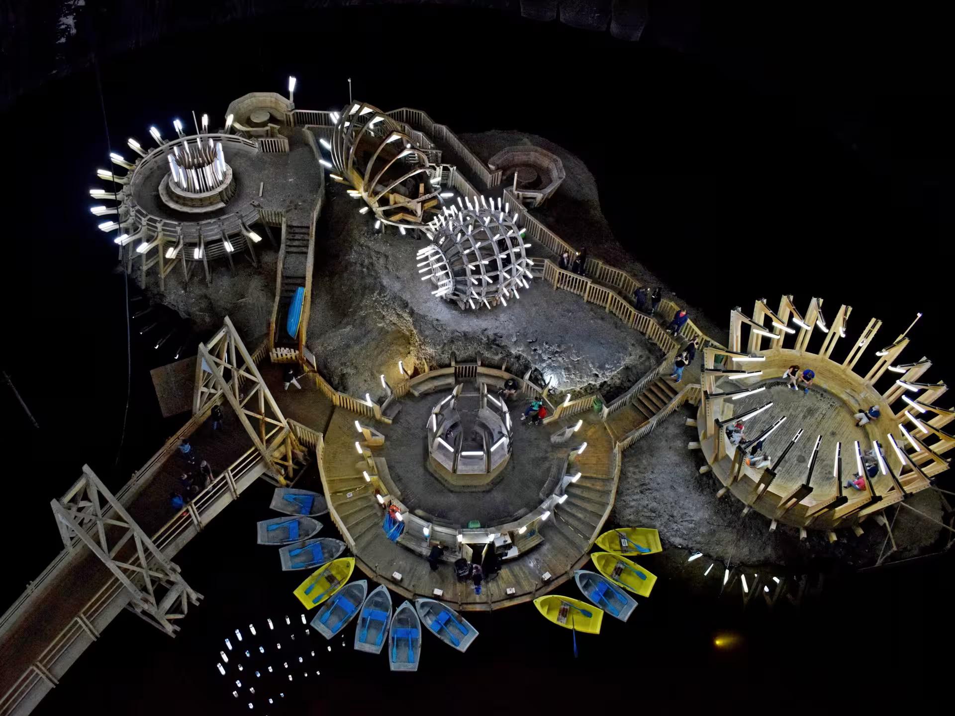 Aerial view of Turda Salt Mine underground island with illuminated wooden structures and colorful rowboats