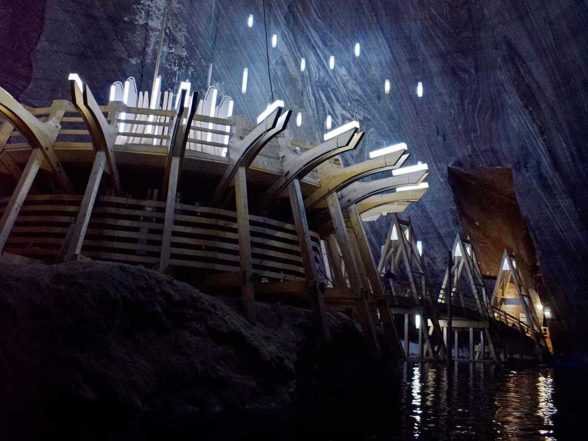Illuminated wooden walkways and underground lake inside Turda Salt Mine on a guided tour from Cluj