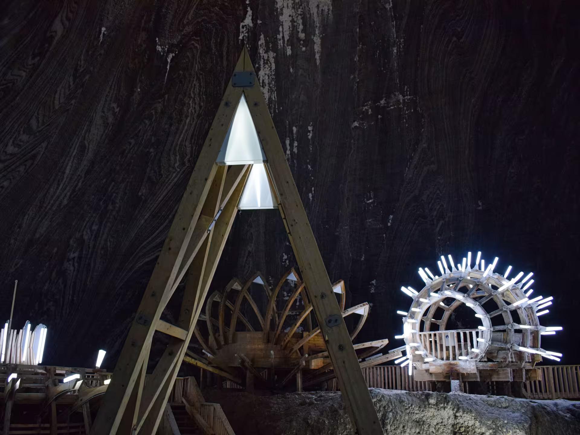 Wooden installations and glowing lights inside Turda Salt Mine's vast underground cavern on a full-day Romania tour.