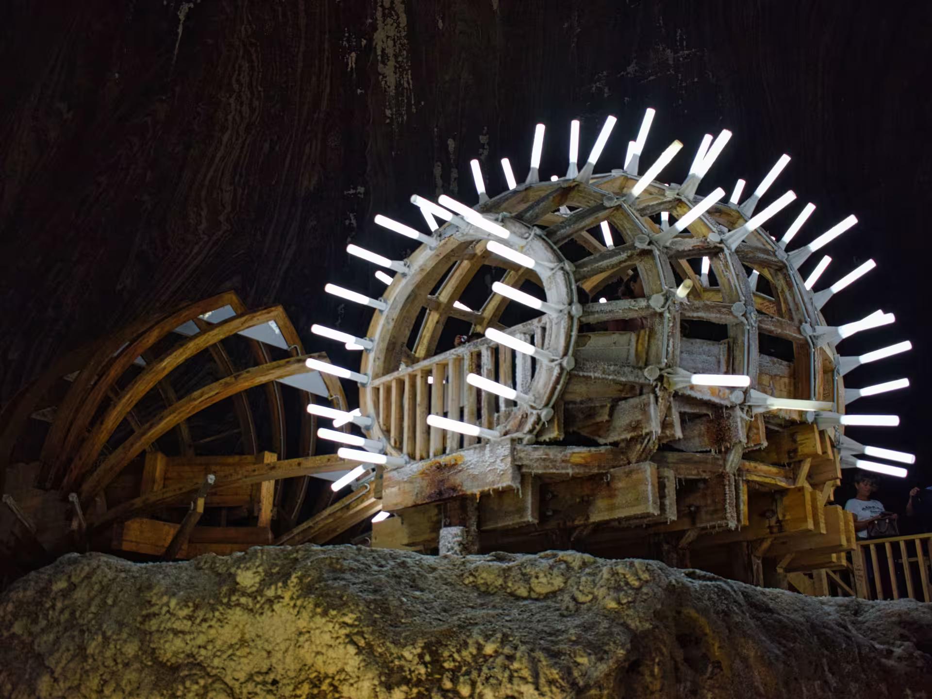 Illuminated ancient wooden salt wheel inside Turda Salt Mine on a guided tour from Cluj Romania