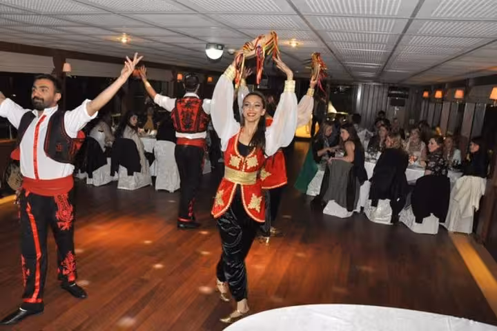 Turkish folk dancers performing on boat dinner cruise, lively Turkish Night show with traditional costumes