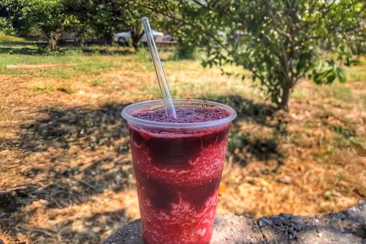 A refreshing cup of traditional Turkish fruit juice sits against a scenic rural backdrop, inviting exploration.