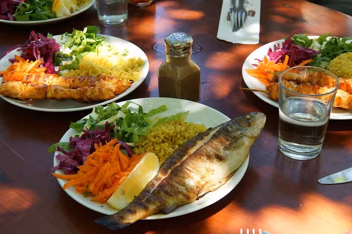 Delicious Turkish meal with grilled fish, rice, and colorful vegetables served on a wooden table in Fethiye.