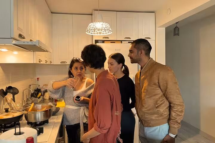 Small group learns Turkish home cooking in an Istanbul city center kitchen, tasting sauce and simmering pots
