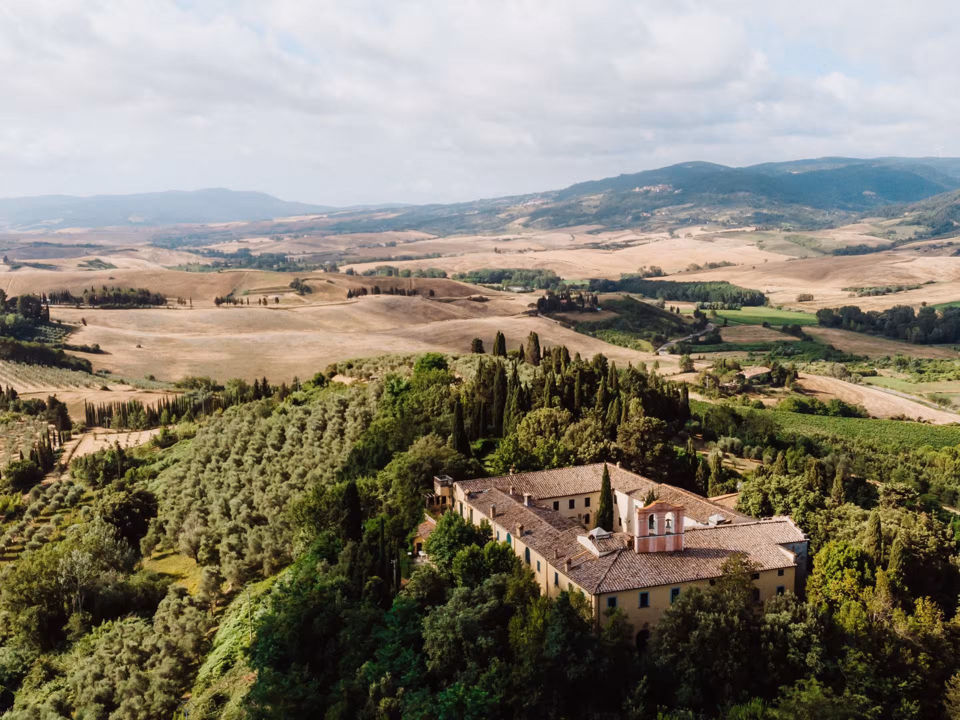 Aerial view of a historic Tuscan abbey nestled in lush countryside, ideal for wine tours near Pisa.