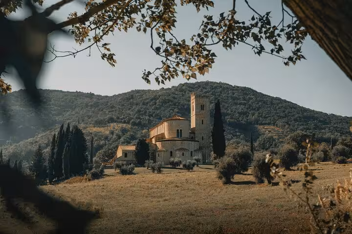 Scenic view of a historic Tuscan villa surrounded by hills and cypress trees in Montalcino.