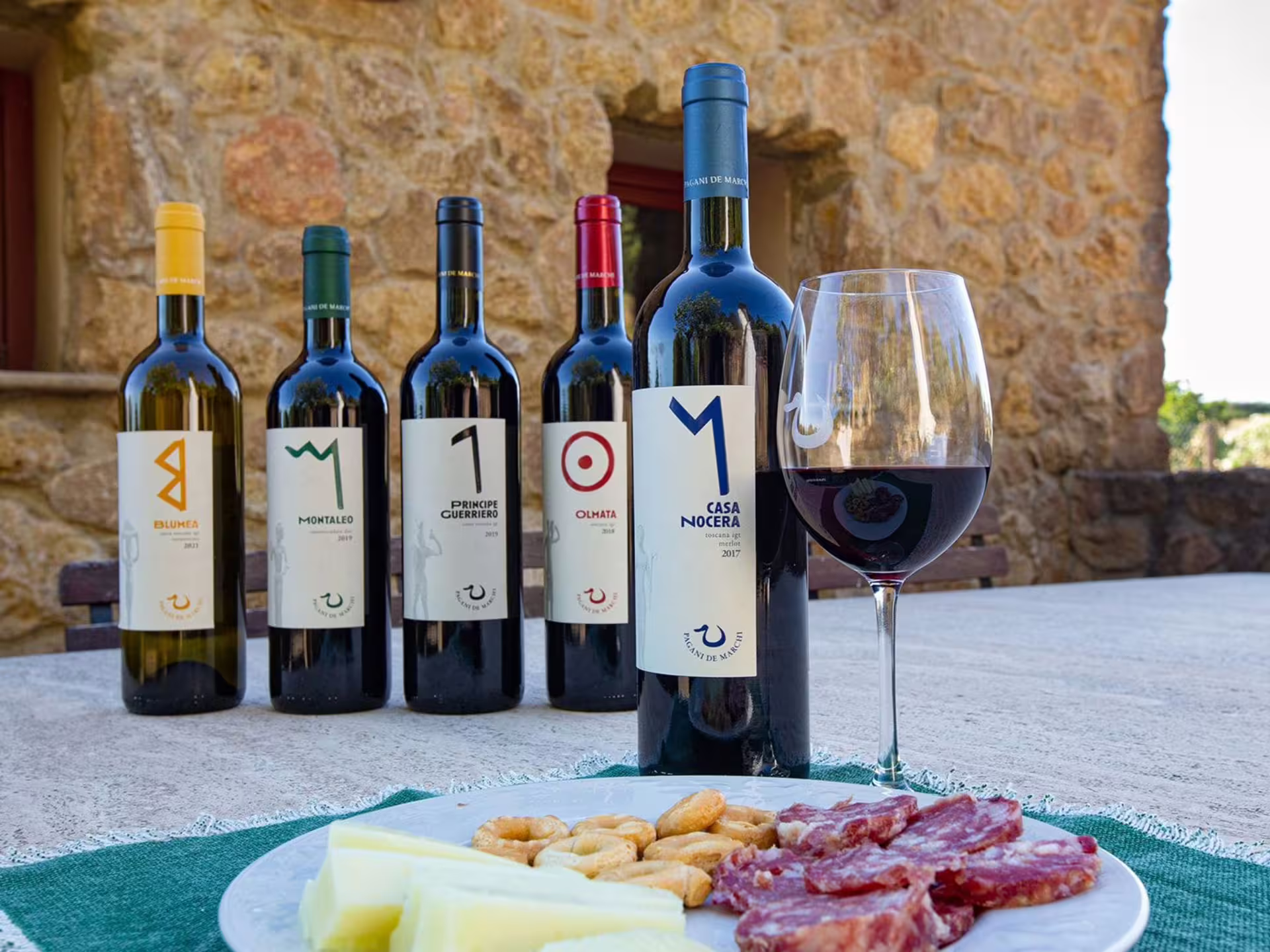 Selection of Tuscan wines with cheese and charcuterie platter at a scenic winery near Livorno and Pisa.
