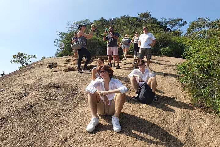 Tourists resting and capturing photos on a rocky outcrop during a guided hike in Two Brothers Hill.