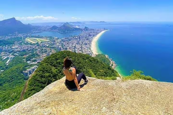 Traveler enjoys breathtaking view from Two Brothers Hill overlooking Rio's coastline and cityscape on a sunny day.
