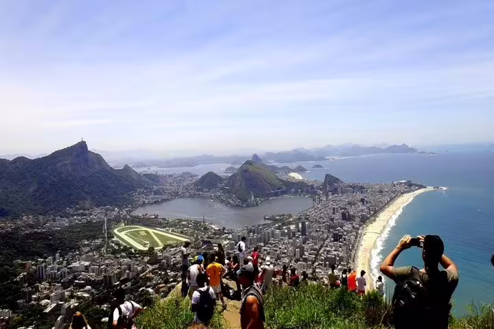 Tourists capturing stunning vistas of Rio's skyline and beaches from Two Brothers Hill viewpoint.