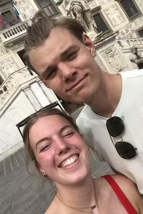 Happy couple smiling during a self-guided mystery puzzle walking tour adventure in Pisa Italy