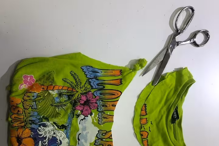 Green T-shirt cut with scissors for upcycling into a tote bag, sustainable bag design workshop materials