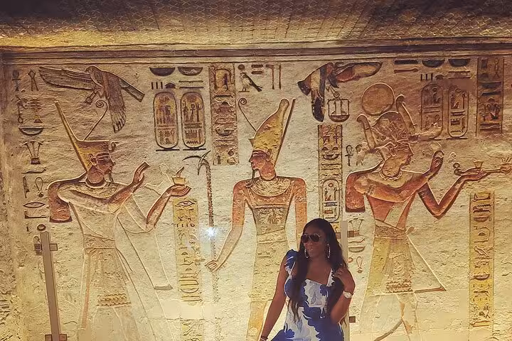 Visitor admiring colorful wall reliefs in a Valley of the Kings tomb during a private Luxor tour experience