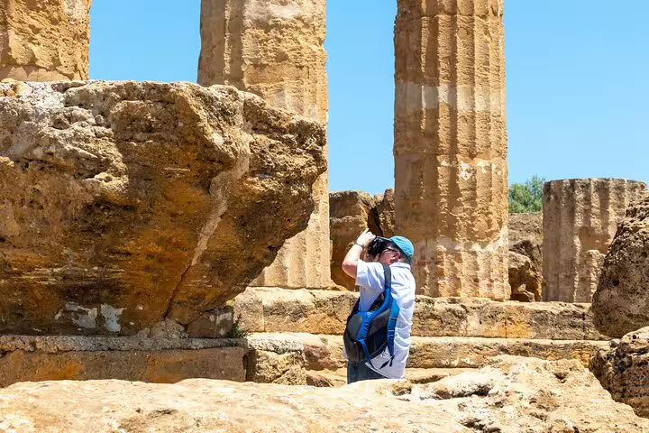 Traveler photographing ancient Greek temple ruins in the Valley of the Temples during a private guided tour in Agrigento