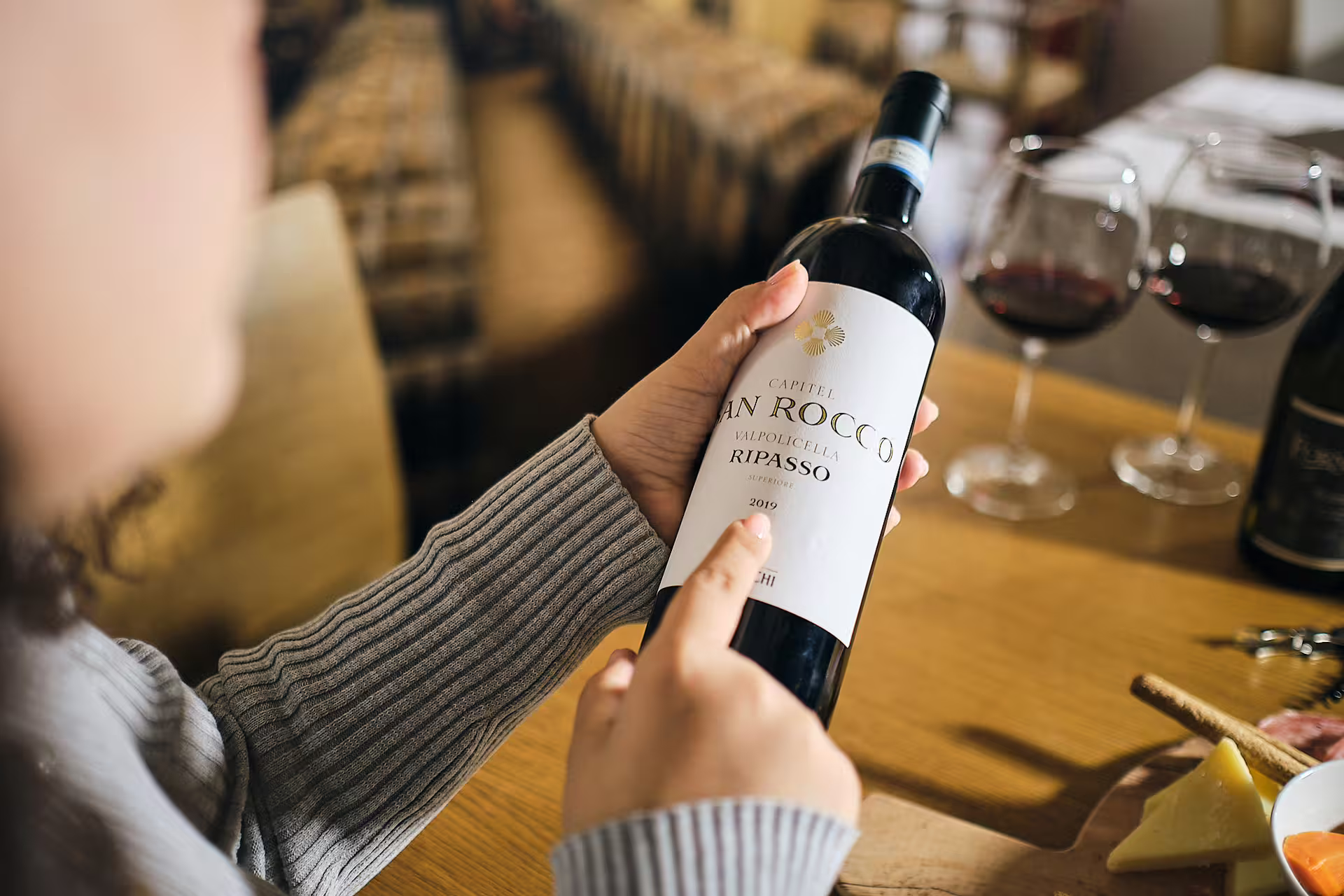 Guest reading Valpolicella Ripasso label during Verona wine tasting near Juliet’s House with red wine glasses