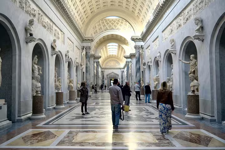 Visitors walk through statue-lined gallery in Vatican Museums on exclusive fast track Sistine Chapel group tour in Rome