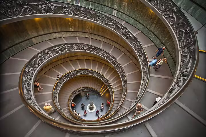 Visitors walking down the ornate spiral staircase inside the Vatican Museums on an Exclusive Sistine Chapel fast track group tour