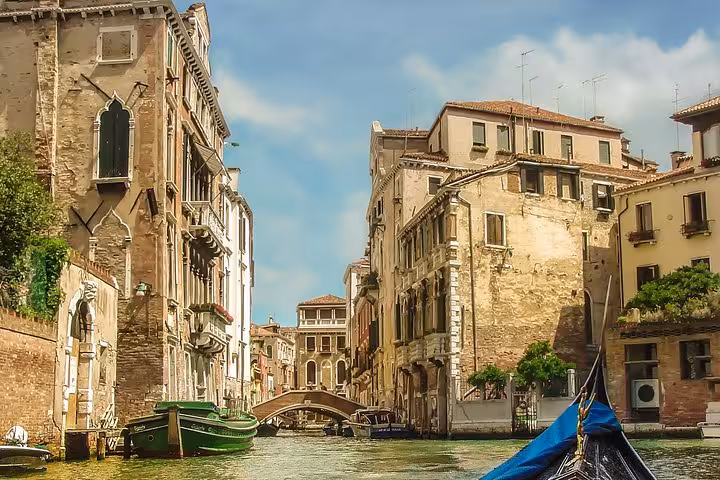 Scenic view of Venice canal with historic buildings and bridge, ideal for a picturesque gondola ride experience.