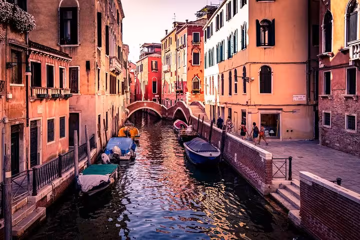 A picturesque canal in Venice with moored boats and colorful buildings, part of a scenic walking and gondola tour.
