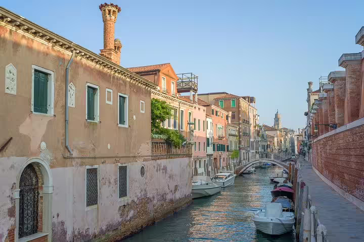 Quiet canal in Venice’s Sestiere Dorsoduro with pastel palazzi, moored boats and bridge seen on Accademia Gallery private tour