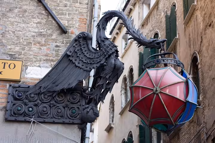 Ornate black metal dragon sculpture with red lantern on a historic Venice building for walking tour attraction.