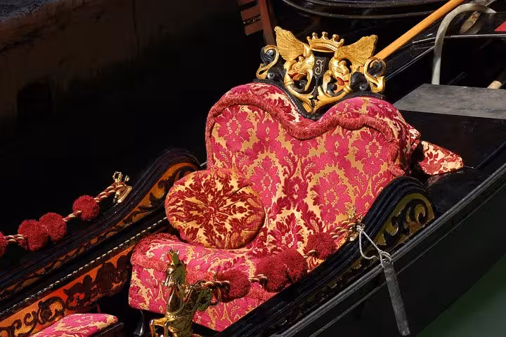 Luxurious red and gold velvet seat with intricate carvings in a traditional Venice gondola for romantic tours.