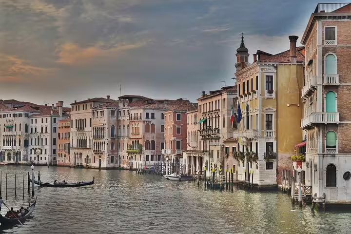 Quiet Grand Canal at sunset with gondolas gliding past ornate palaces on a hidden corners private Venice tour