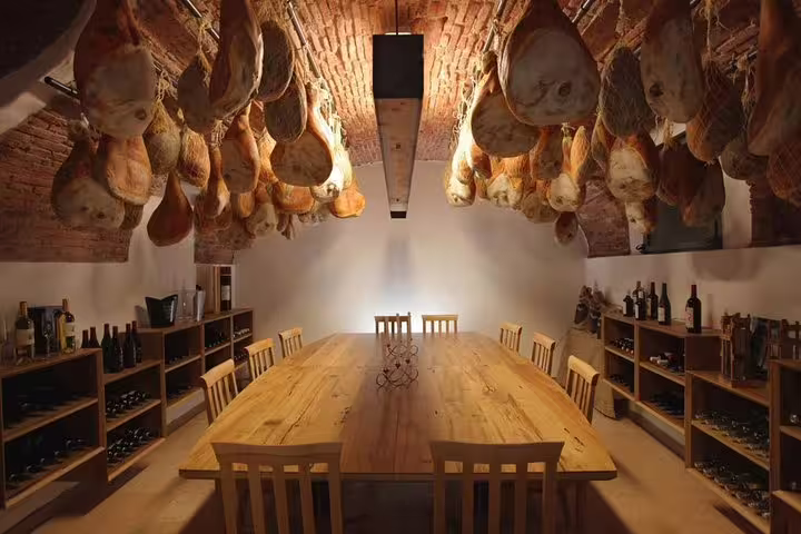 Elegant cellar dining setup with cured meats and wine, highlighting culinary delights on Venice to Milano scenic transfer.