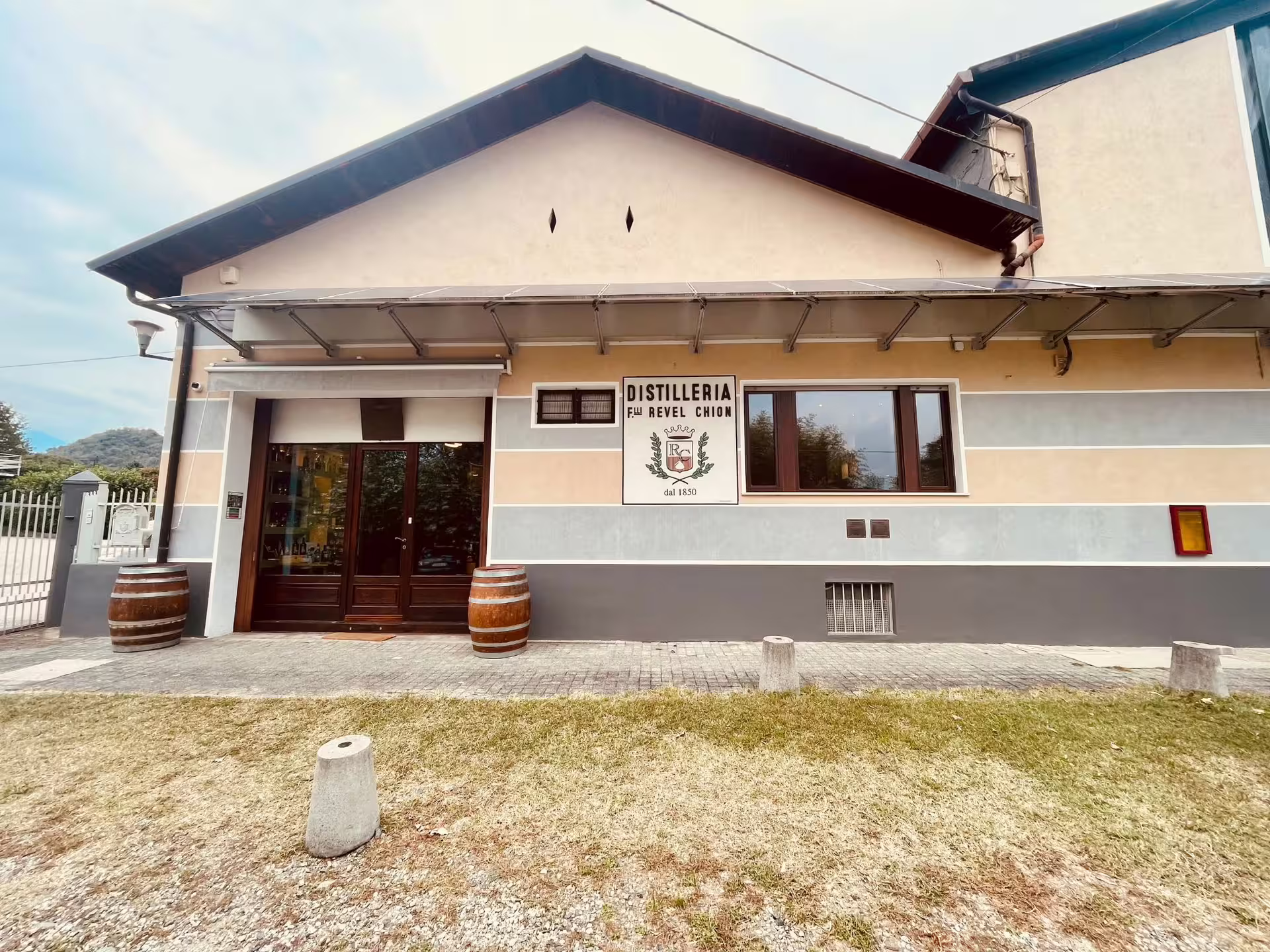 Front view of a historic distillery near Turin, featuring a welcoming entrance with wooden barrels.