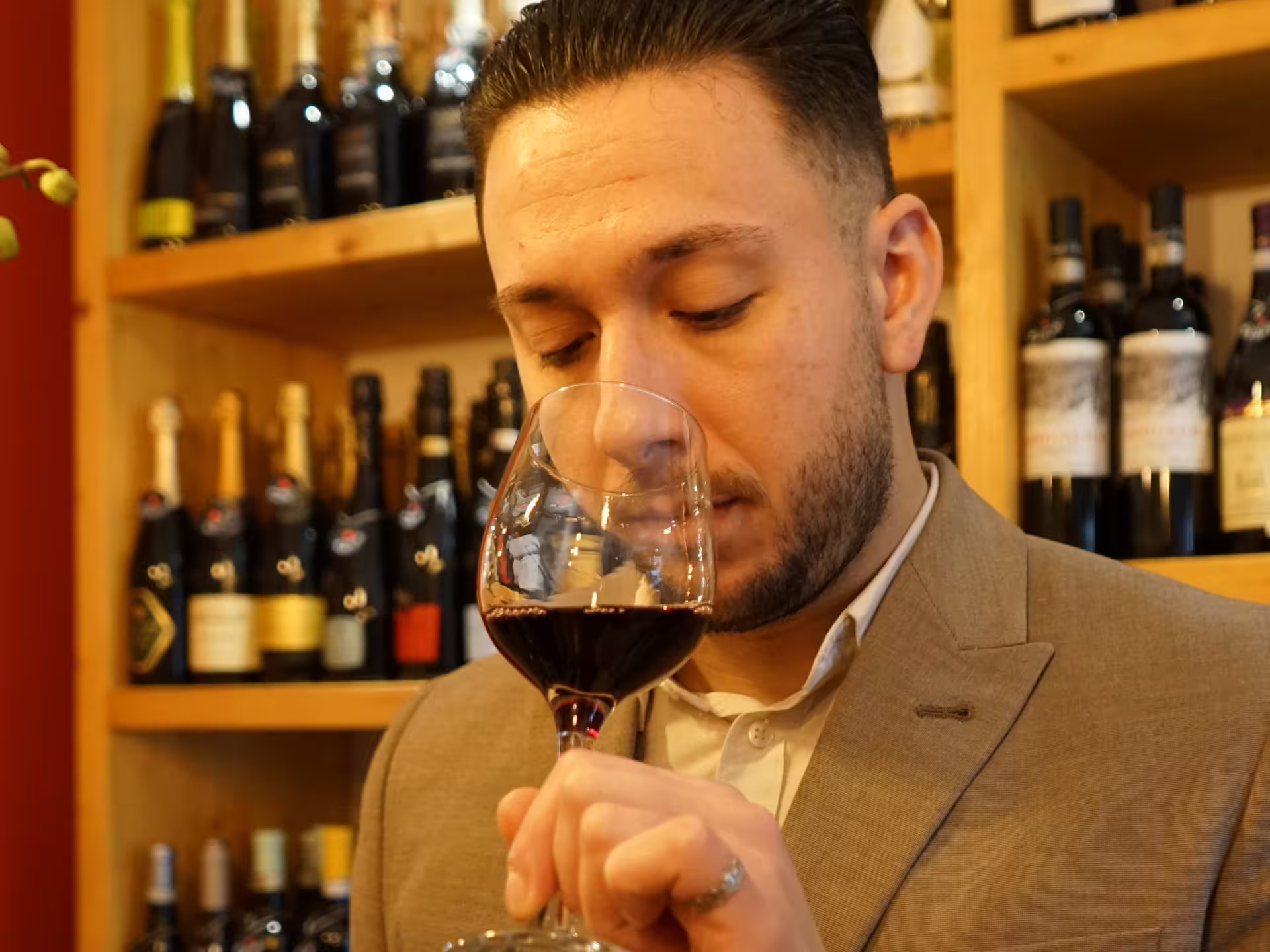 Man savoring vermouth aroma during tasting session in Turin city center, surrounded by wine bottles.