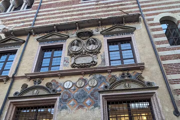 Historic facade in Verona with ornate windows and fresco details, seen on a live guided walking tour route