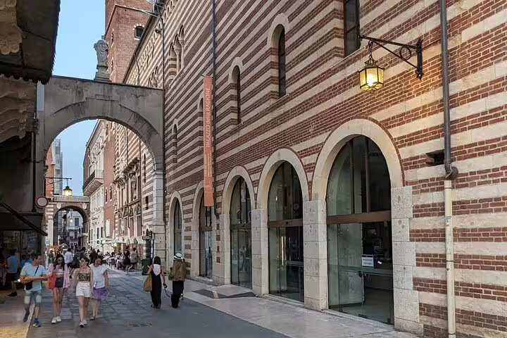 Verona historic street by striped Palazzo del Capitano near archway, seen on live guided walking tour