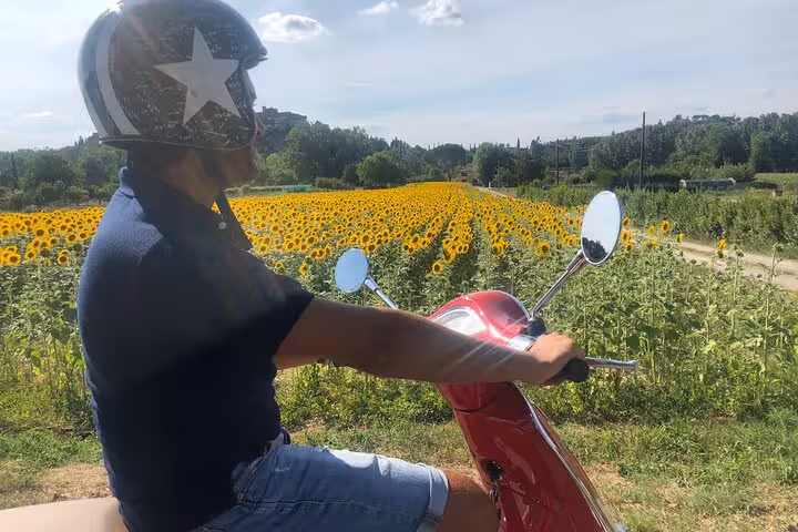 Ride a Vespa through vibrant sunflower fields in Tuscany, capturing the essence of a scenic Florence tour.
