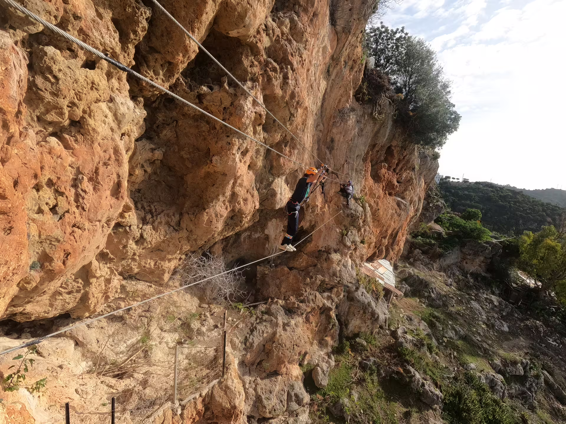 Adventurers cross a rugged cliffside on a Via Ferrata in Casares, enjoying breathtaking views and challenging climbs.