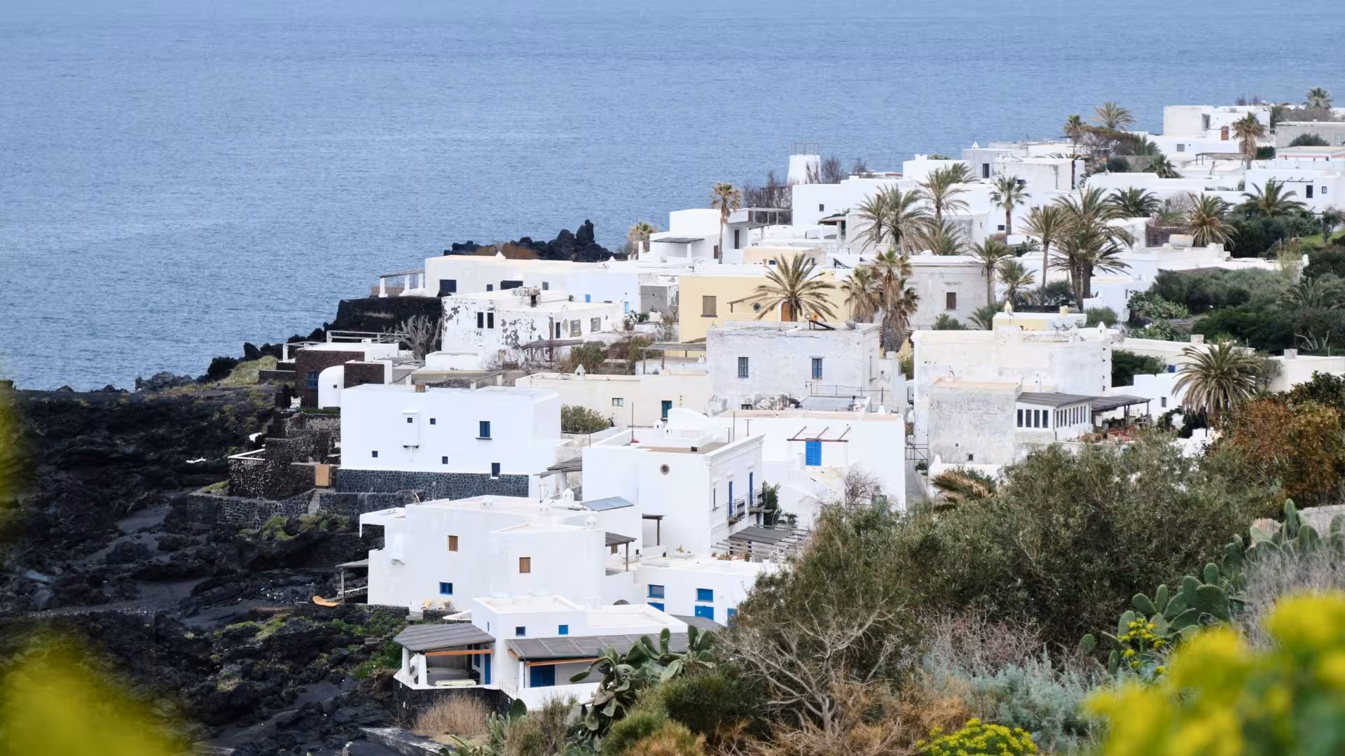Scenic view of whitewashed houses and lush greenery overlooking the sea in the Aeolian Islands, perfect for exploration.